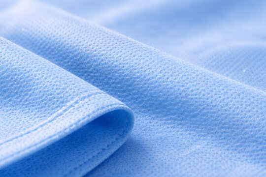 Photorealistic 3D macro product-shot of an unbranded sterile surgical drape folded into a neat square, visible nonwoven fabric microtexture and subtle creases, clean sealed edges
