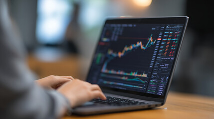 A person analyzing stock market data on a laptop computer screen at a desk