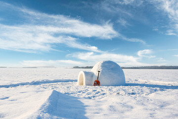 Snow igloo in the winter field under blue sky with fluffy clouds. Landscape photography