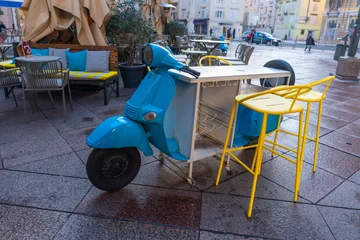Fototapeten Roller Creative outdoor cafe setup featuring a vintage blue scooter transformed into a bar  © TatiG