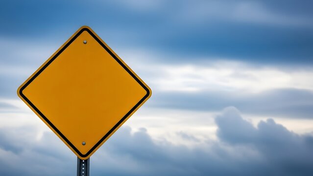 A blank yellow diamond shaped road sign against a cloudy blue sky