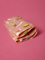 A vibrant rolled dessert featuring layers of pink and white with nuts embedded. Perfect for dessert presentations and culinary showcases.