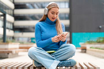 Woman using smartphone while listening to music outdoors in a city setting