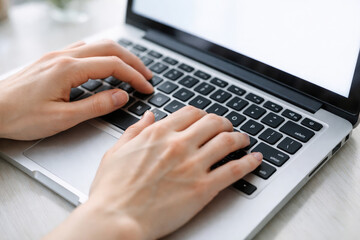 Hands typing on a laptop keyboard with fingers visible above the keys and a light surface underneath the computer