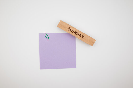 Wooden block with a word Monday and blank note on a white background. Minimal business concept of daily planning, schedule, tasks, productivity and time management with copy space.