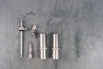 Set of metal socket wrench attachments on gray surface