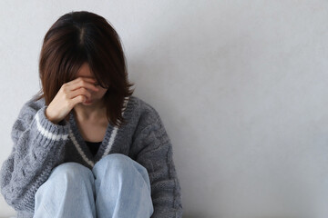 目を覆って落ち込む女性の後ろ姿