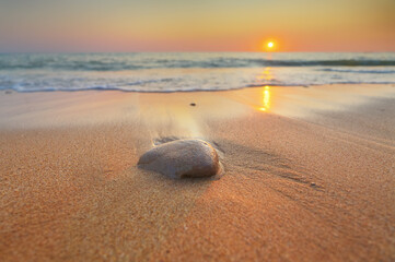 Nature landscape of stone on sandy beach. Close up view of smooth wet pebbles on a sea shore at the sunset.