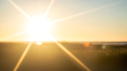 Warm sunset lens flare over blurred natural field background with starburst