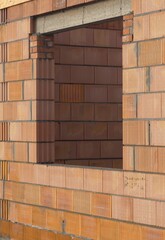 Otwór przygotowany na okno w wymurowanej ścianie domu. Surowa konstrukcja pokazuje etap prac budowlanych. © Adam