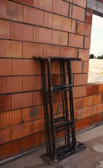 Rusztowania stoją przy ścianie murowanego domu, wnętrze w fazie budowy. Widoczne belki, ściany i przygotowanie do dalszych prac. © Adam