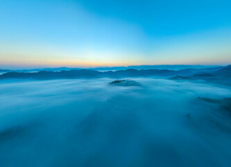 Aerial view of flowing fog waves on mountain tropical rainforest,Bird eye view image over the clouds Amazing nature background with clouds and mountain peaks in Thailand