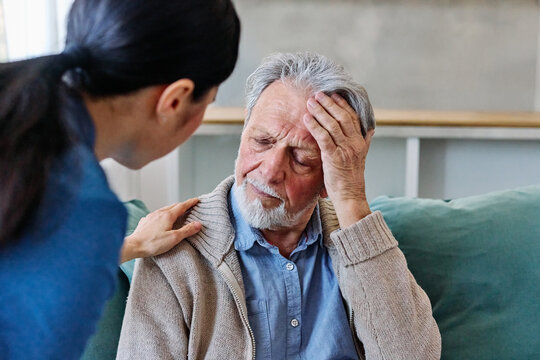 Doctor or nurse caregiver's hand giving support to sad lonely senior man at home or nursing home