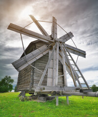 Old wooden windmill on a meadow at cloudy day.