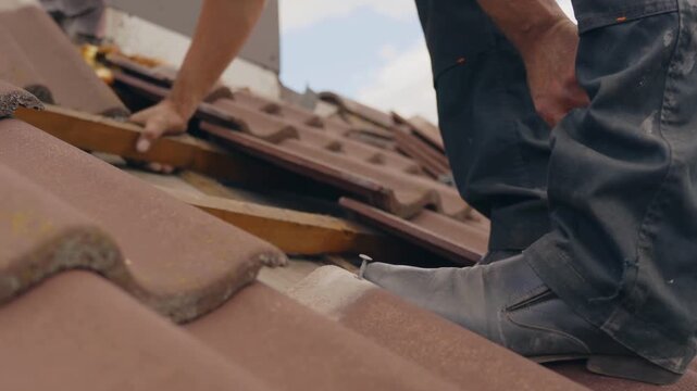 roofer pulling out nails from roof tiles repairing work.