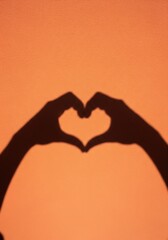 Obraz premium Shadow Of Hands Forming Heart On Terracotta Wall