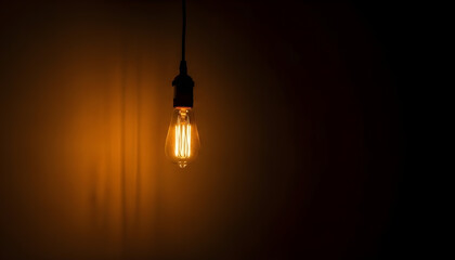 An illuminated glass light bulb hanging in the dark glows with bright electric energy, symbolizing a powerful concept of innovation and a sparking idea for new technology