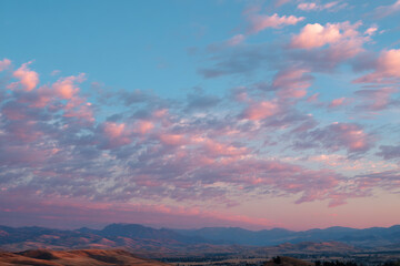 Obraz premium Serene mountain landscape with pink clouds at sunset