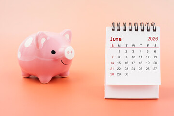 Desk calendar for June 2026 and pink piggy bank.