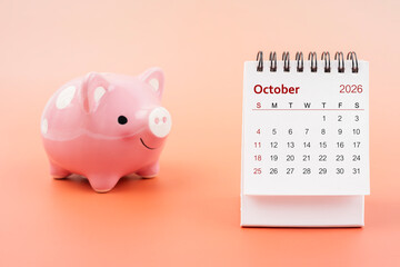 Desk calendar for October 2026 and pink piggy bank.