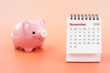 Desk calendar for November 2026 and pink piggy bank.
