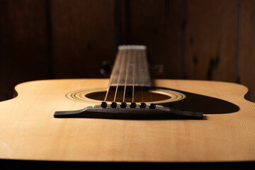 Close-up acoustic guitar, focusing on the strings, bridge, and smooth wooden body.