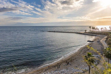 Obraz premium View of the Mediterranean Sea from a Benalmádena viewpoint at sunset, with few clouds and part of the city visible to the side, creating a warm and scenic coastal scene.