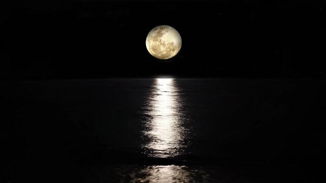 Full moon shining brightly over the calm ocean reflecting its light on the water