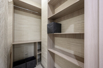  A built-in wardrobe with light wood finish, open shelves, a hanging rod, and black storage boxes. Clean lines, minimalist design, functional layout