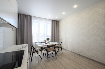 modern kitchen with marble-like countertop, white cabinetry, light wooden flooring. Dining table...