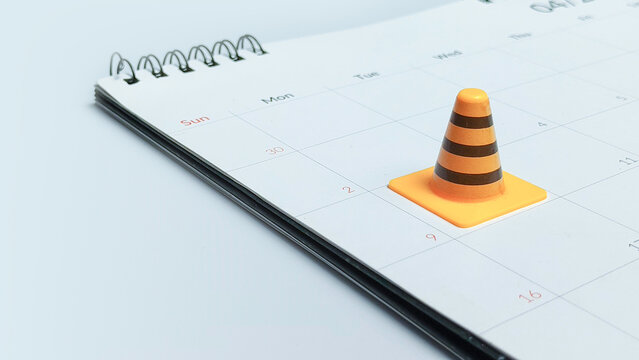 Project deadline and construction schedule concept with orange traffic cone on calendar page