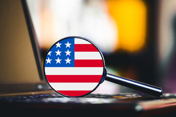 Magnifying glass with USA flag over laptop keyboard. American market research and data analysis concept. United States economy business search idea. Closeup technology background for finance theme