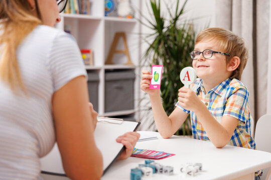 Child Learning Alphabet with Teacher Using Flashcards in Classroom