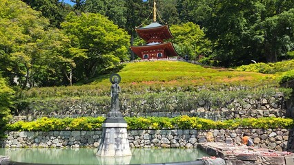 Scenic view of red pagoda and Buddhist statue standing in a pond at Katsuoji Temple in Osaka