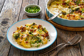 Potato broccoli casserole - baked potatoes with broccoli, cheddar cheese and smoked bacon on wooden...