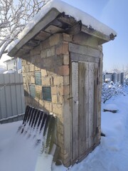 Old Brick Outhouse with Wooden Door and Snow Primitive Backyard Toilet Building in Rural Setting