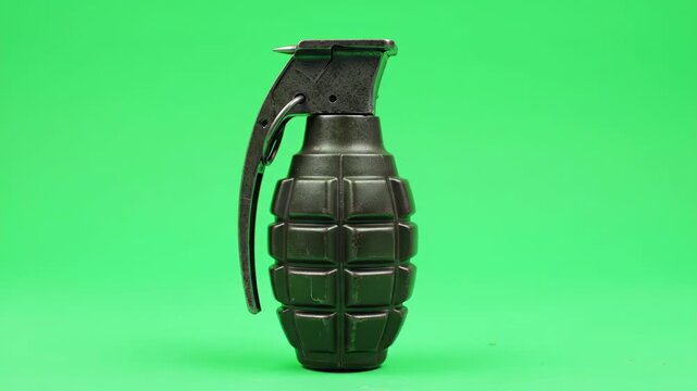 Black hand grenade on a green background with a safety pin