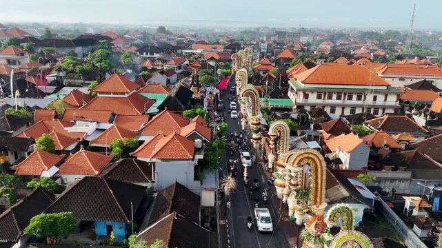 Aerial view of real time drone footage of rows of Penjor decorated with colorful coconut leaves decorating the roadside in Bali