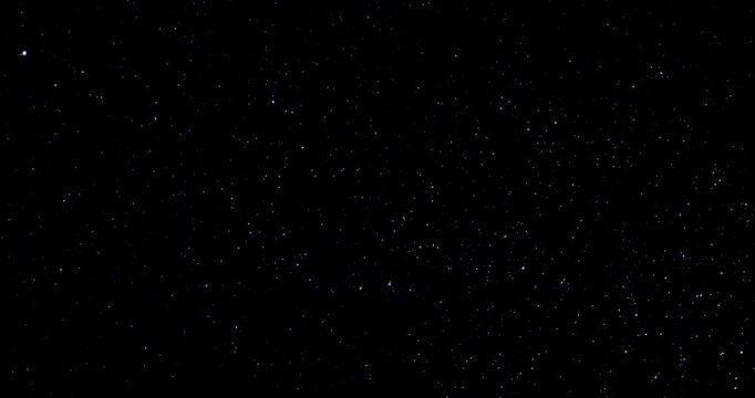 Natural organic dust particles floating dynamically in space against a black background. Shimmering glittering dust with bokeh. This dust is in slow motion.