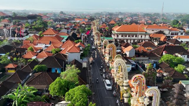 Aerial view of real time drone footage of rows of Penjor decorated with colorful coconut leaves decorating the roadside in Bali