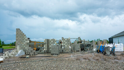 House construction site during hiatus near a completed house (right), with wheelbarrows, a portable...
