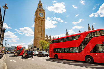 Red double-decker buses traveling past Big Ben in London, UK