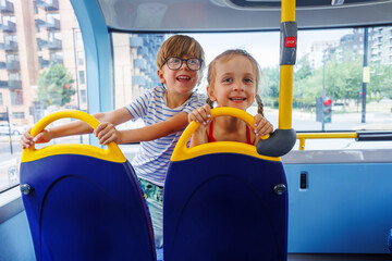 Naklejka premium Two children happily enjoying a bus ride through summer city