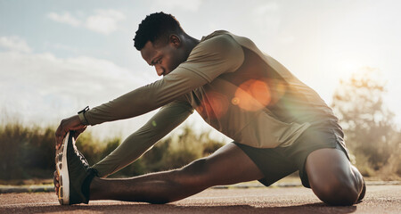 Young black man warming up for run training, fit, active athlete in sports clothes outside on tartan track stretching muscles wearing smartwatch for health and fitness, against sun analog lens flare