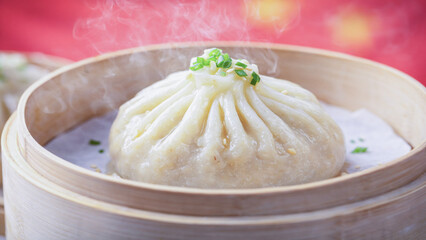 Traditional Chinese steamed dumpling presented in bamboo steamer, cultural food symbol with Chinese flag behind.