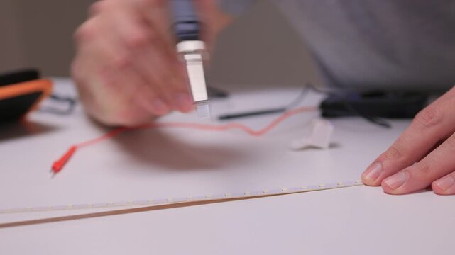 Closeup of soldering process, Electronics hobbyist connecting copper pads using hot iron tool, Detailed view of person soldering wires onto LED strip with precision guidance
