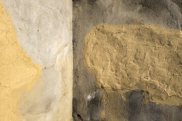 Rustic textured concrete inner corner between walls with colorful cracks outdoors under direct sun light.