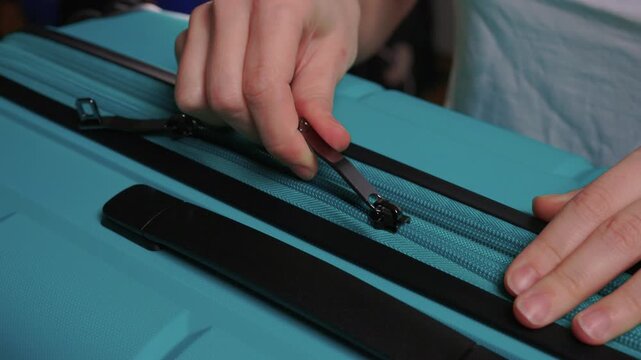 Secure suitcase with combo lock, Hands set combination on teal suitcase with textured surface, Closeup of hands adjusting numeric lock on stylish teal travel suitcase