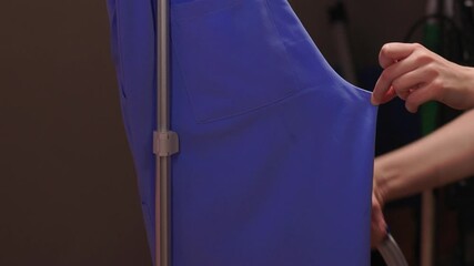 Blue shirt steaming, Blue uniform hanging while expertly steamed for wrinkle removal, Navy blue outfit on hanger being carefully steamed to remove creases professionally
