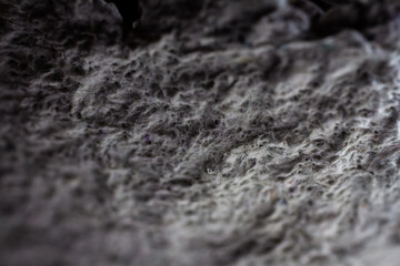 Extreme close up of old gray handmade paper clay with a structure and rough texture. Paper recycling. Selective soft focus, shallow depth of field.